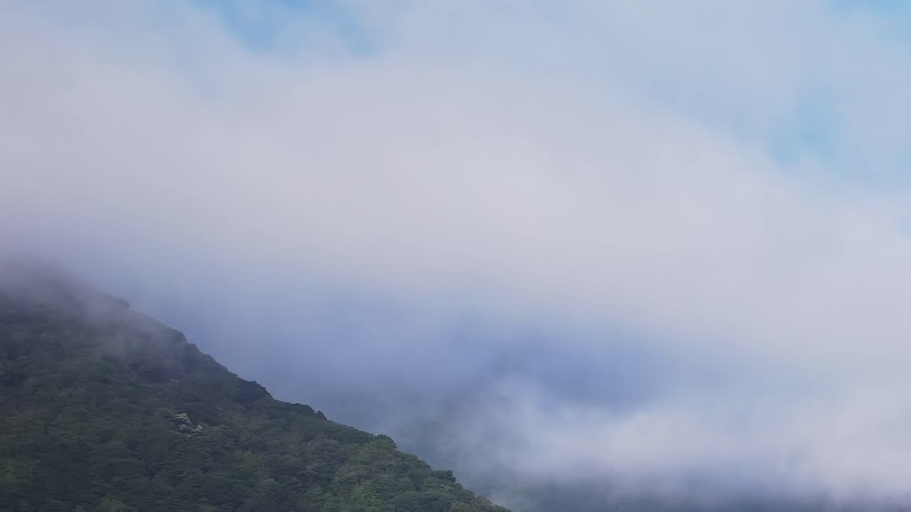 Clouds drift over lush mountains in Madeira, Portugal from above