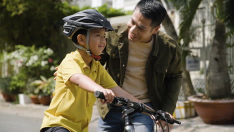 father putting a helmet on his son