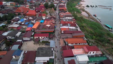 fotografía aérea de una calle y casas de residentes en el distrito de chiang khan a lo largo del río mekong en tailandia, avión no tripulado vuela hacia atrás