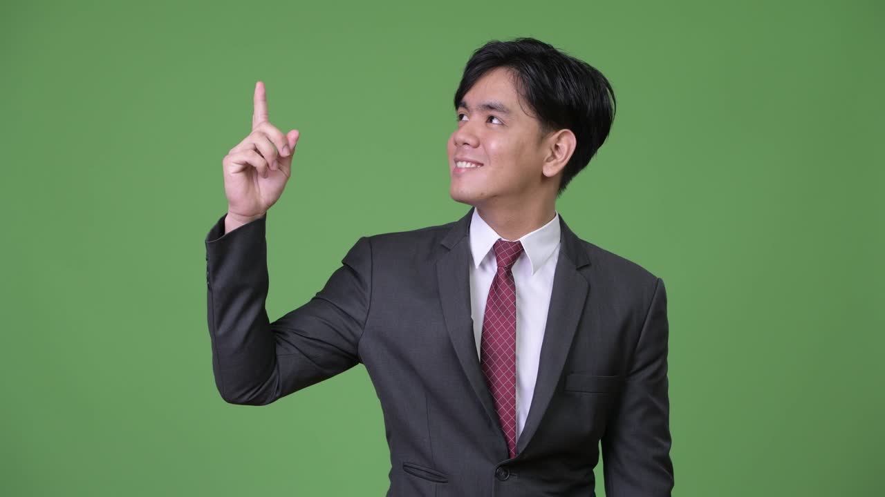 若いハンサムなアジア人ビジネスマンが何かを見せている