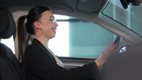 A Young Woman in Glasses Sits in a Car and Examines the Interior of the Car. A young woman in glasses sits in a car and examines the interior of the car. High quality footage