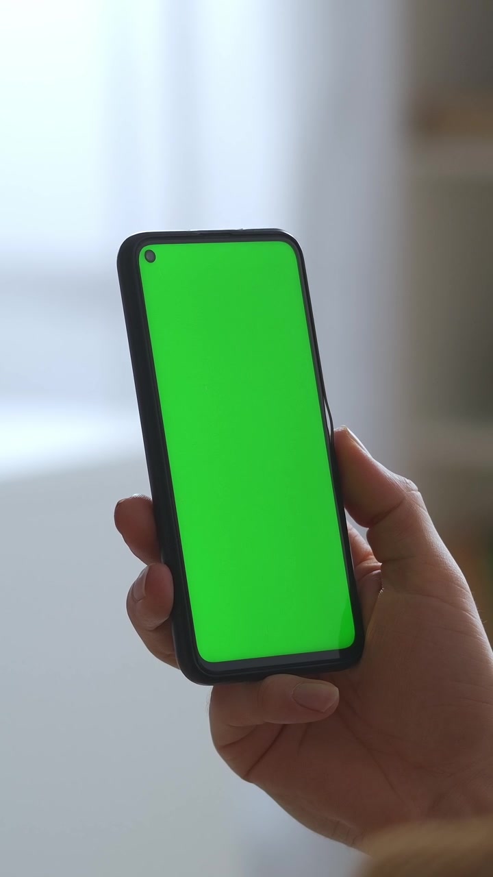 Primo piano di una mano che tiene uno smartphone con schermo verde.