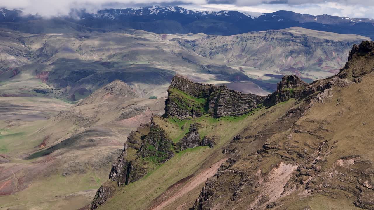 Aerial view of steep mountains and valley of iceland in summer. Snowy peaks of hills in distance. Aerial approaching shot. Wide shot. Vik, Hatta.