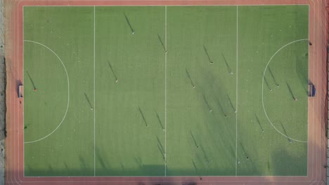 Zeitraffer-Aus-Der-Luft-Von-Oben-Nach-Unten-Des-Hockeyspielers,-Der-Während-Des-Sonnenuntergangs-Auf-Dem-Grünen-Hockeyplatz-Spielt