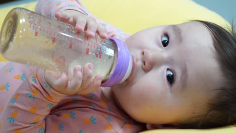 Süßes-Kleines-Mädchen,-Das-Sich-Hinlegt-Und-Eine-Flasche-Milch-Trinkt---Nahaufnahme