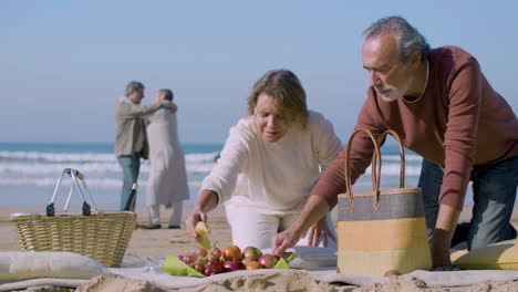 una encantadora pareja de mayores haciendo picnic en la playa del océano.