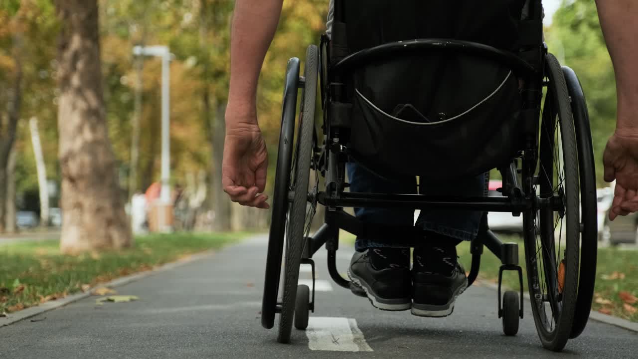 hombre con discapacidad en silla de ruedas camina por el callejón del parque