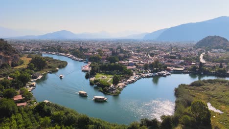 drone shooting of the river and river channel with pleasure boats against the backdrop of the beautiful city of dalyan turkey among greenery and houses