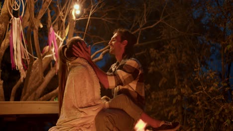 a brunette with long hair strokes his girlfriend covered with a blanket. relax in a country house, evening near the fire