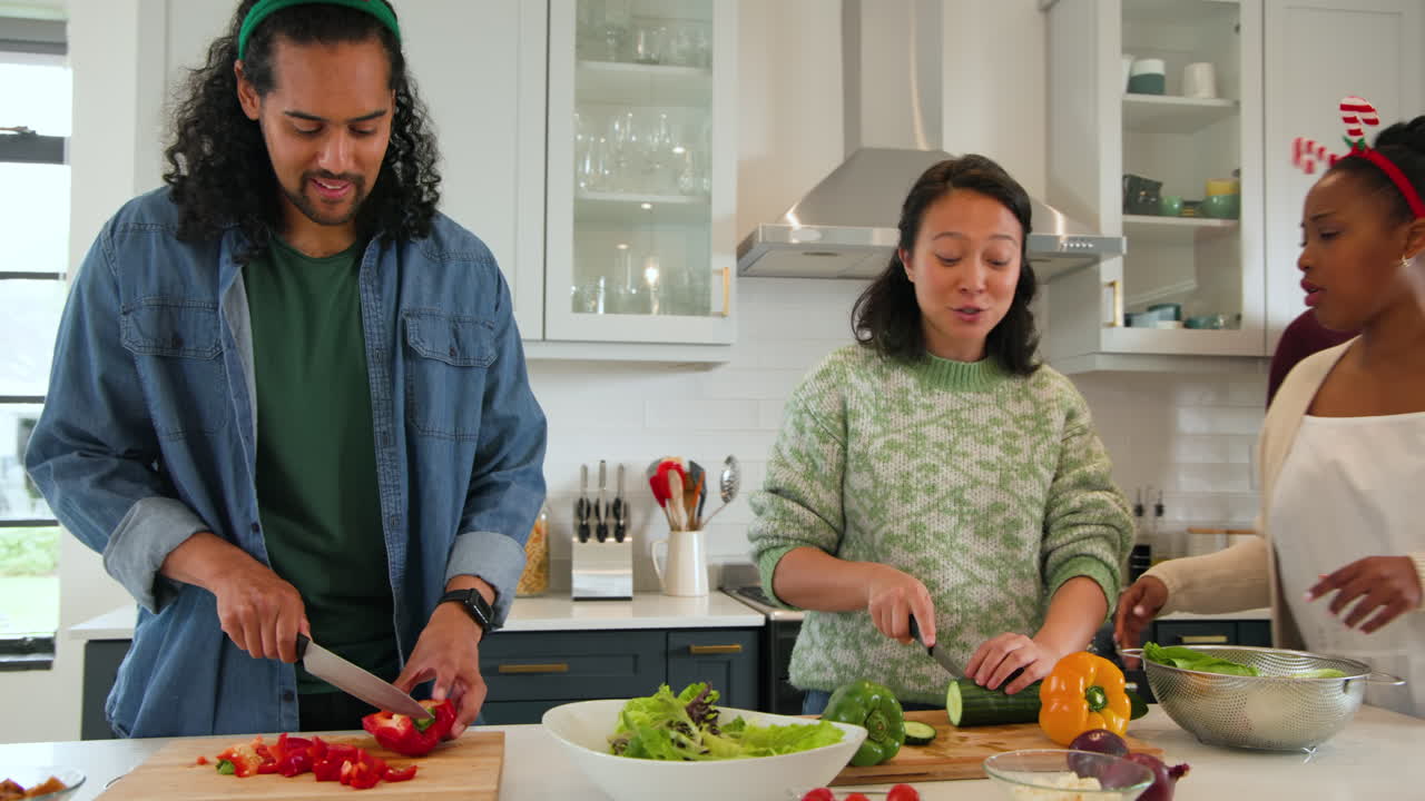 At Christmas, diverse friends preparing festive meal together in kitchen, wearing holiday headbands