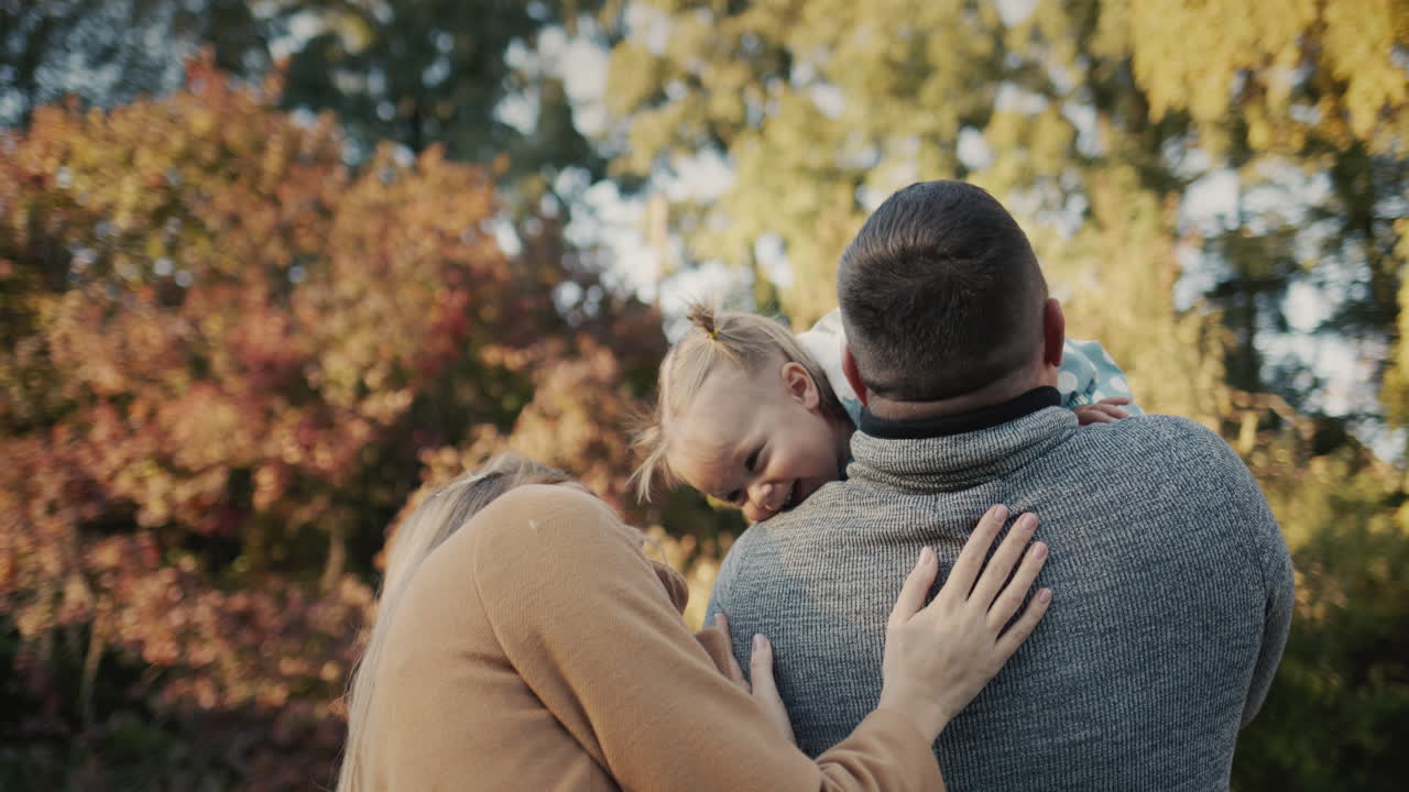 una pareja alegre de padres jugando con su hija pequeña en el parque. riendo, teniendo un buen tiempo juntos