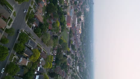 coches que pasan por casas suburbanas enmascaradas por el humo de los incendios forestales que causan mala calidad del aire y baja visibilidad