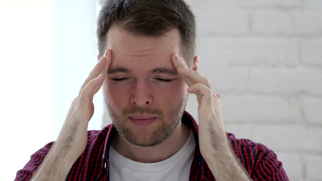 dolor de cabeza, joven tenso en el trabajo en la oficina, biblioteca