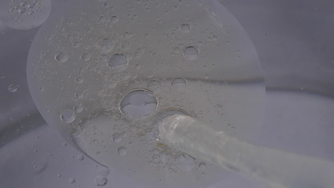 하향식 근접 촬영, 드롭퍼 피펫이 흰색 배경에 있는 물에 기름을 배출합니다.