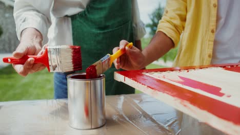 two people painting wooden shutters outdoors