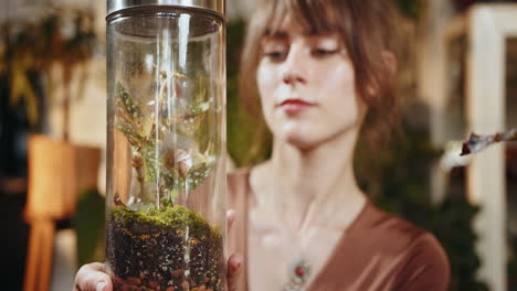 woman examining a terrarium plant