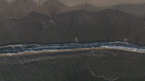 Aerial-view-of-kids-playing-on-the-sandy-beach-in-front-of-perfect-waves-breaking-on-the-shore