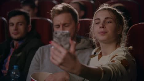 girl making selfie photo with boyfriend at cinema. love couple taking photo