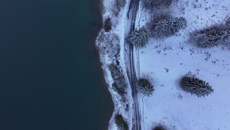 aerial view of snow-covered lake shores and a winding road along the banks of klöntalersee in glarus, switzerland.