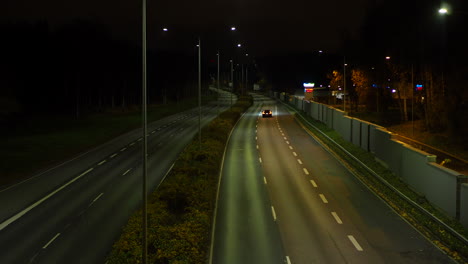 Coche-Negro-Conduciendo-Solo-En-Una-Carretera-Vacía-Por-La-Noche