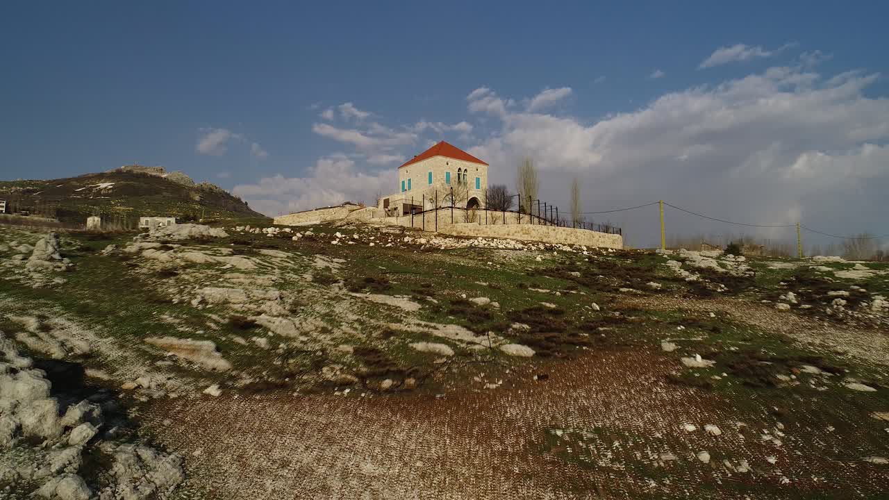 Low aerial pull back view of Akoura House, rocky terrain and blue sky, Lebanon