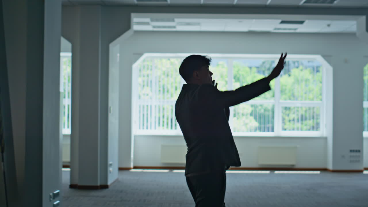 Formal manager silhouette calling smartphone at modern architecture building