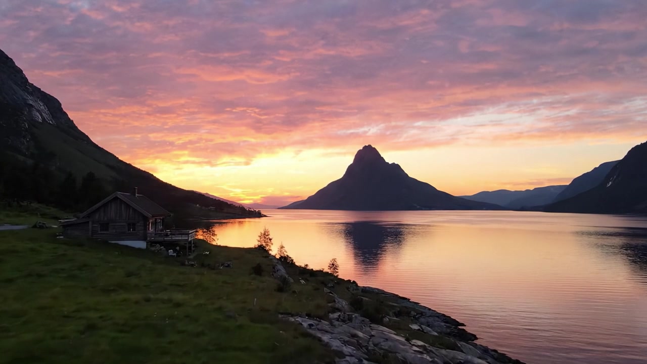 Un glorioso tramonto su un lago sereno che cattura la bellezza tranquilla della natura con colori vivaci che si riflettono sull'acqua e maestose montagne sullo sfondo.