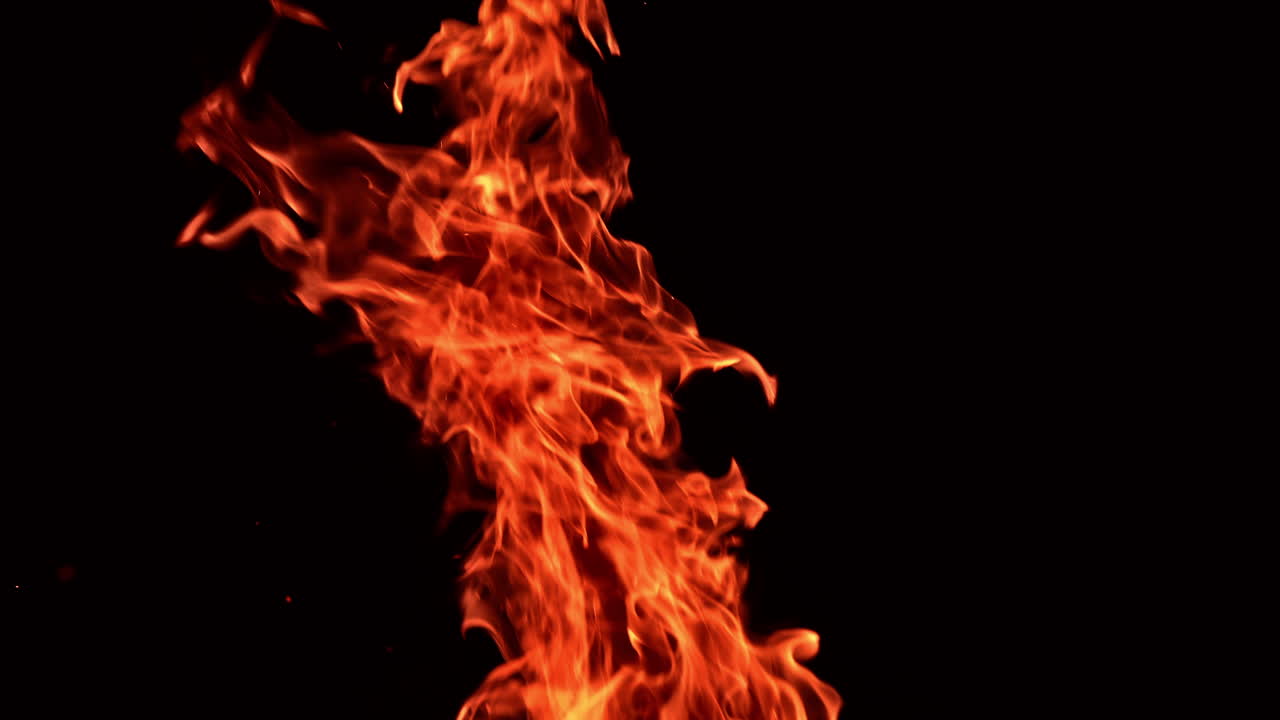 Red hot fire flame rising into air. Burning bonfire upper part isolated at black backdrop.