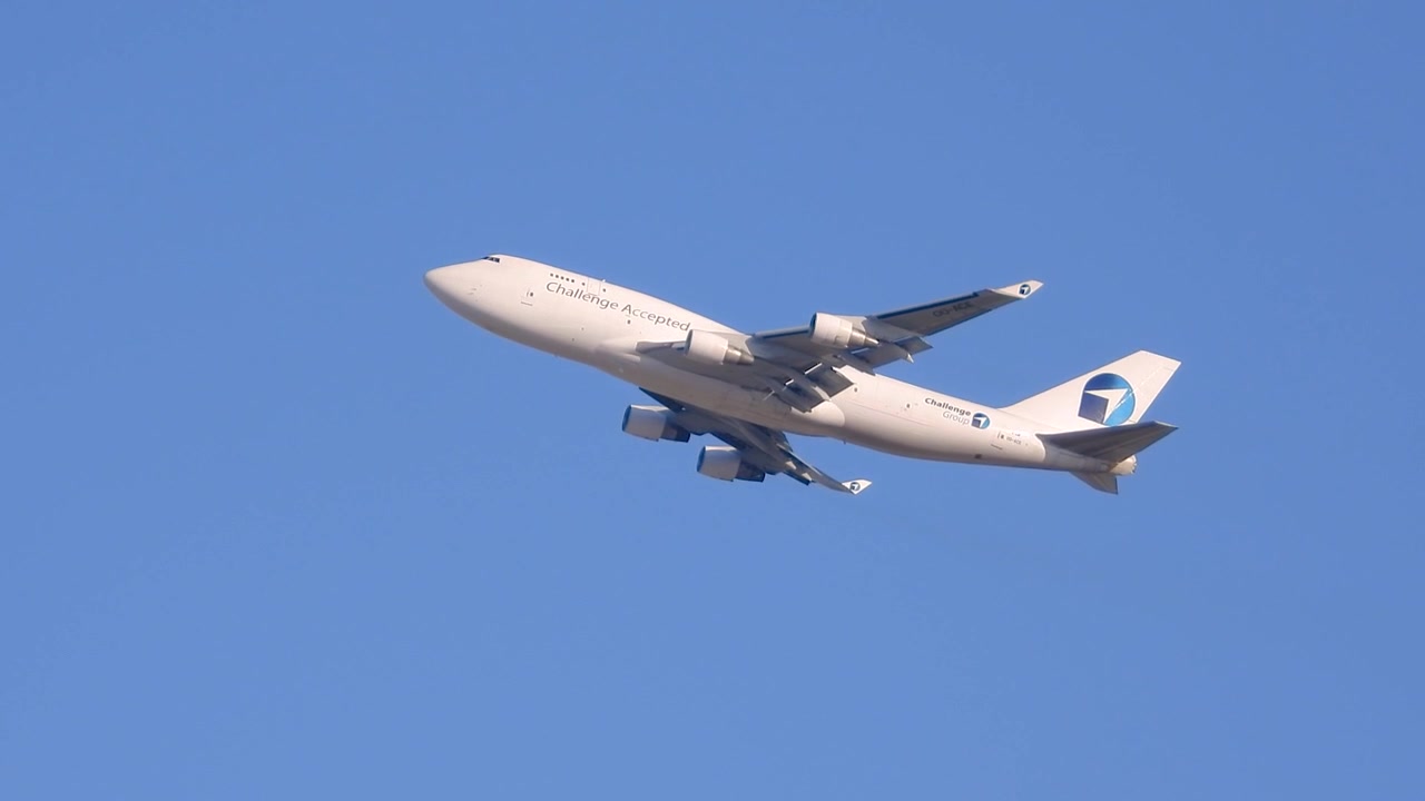 日中の澄み切った青空を背景に上昇する大型旅客機を下から撮影。