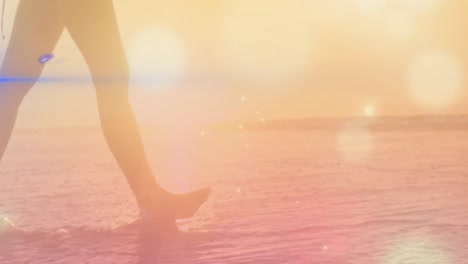 Animation-of-light-spots-over-woman-walking-at-beach