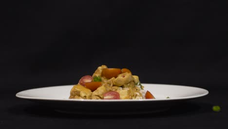 Close-up-shot-of-steamy-hot-chicken-curry-with-herbs-falling-onto-it