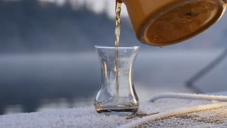 pouring black tea (chai) beside a cold lake