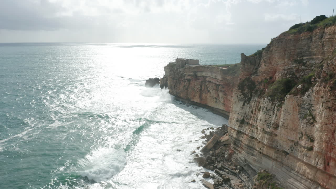 Aerial reveal of the beautiful old fortress Fort of São Miguel Arcanjo (St. Michael the Archangel) standing on a cliff surrounded by a wild sea