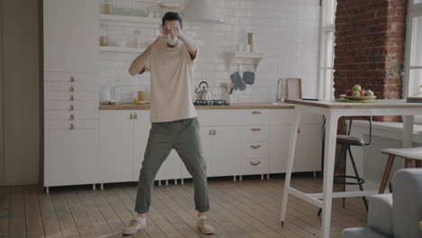 man dancing in kitchen with headphones and coffee