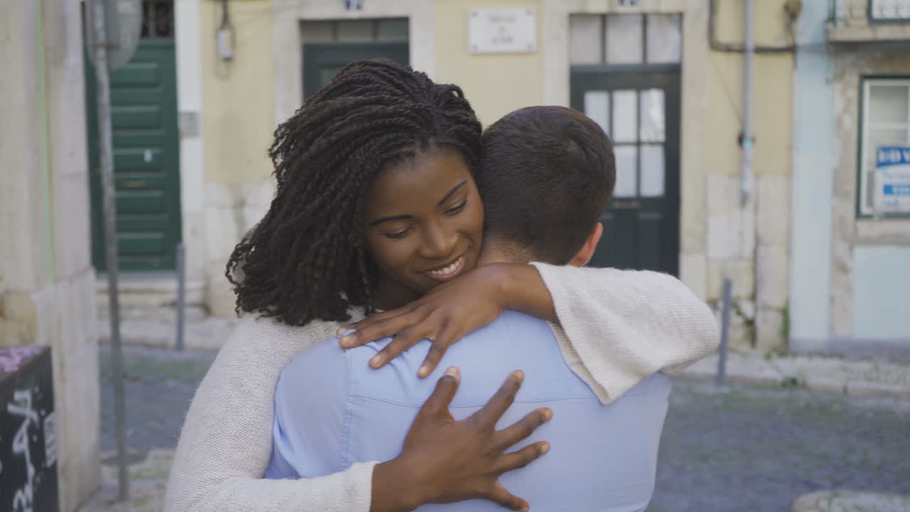 Smiling woman with dreadlocks hugging her boyfriend.