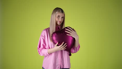 Loving-woman-holds-and-hugs-a-red-heart-balloon,-isolated-yellow-background