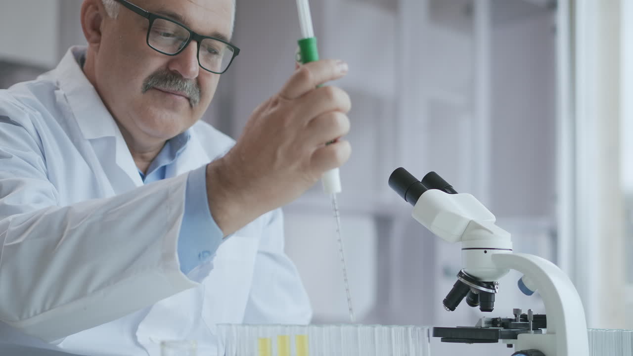 laboratorio. mano en guante azul mueve los tubos y gotea líquido azul. trabajador médico sosteniendo muestra de líquido amarillo y azul en tubo de ensayo analizando orina en laboratorio. imágenes de alta calidad 4k