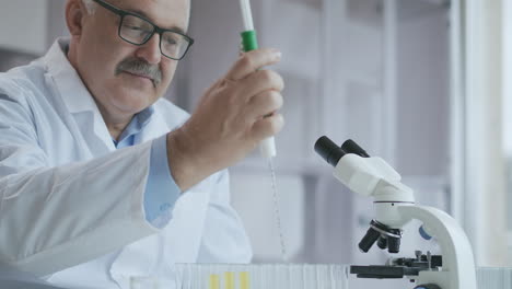 Laboratory.-Hand-in-blue-glove-moves-the-tubes-and-drips-blue-liquid.-Medical-worker-holding-yellow-and-blue-liquid-sample-in-test-tube-analyzing-urine-in-lab.-High-quality-4k-footage