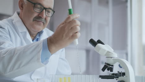 laboratorio. mano en guante azul mueve los tubos y gotea líquido azul. trabajador médico sosteniendo muestra de líquido amarillo y azul en tubo de ensayo analizando orina en laboratorio. imágenes de alta calidad 4k