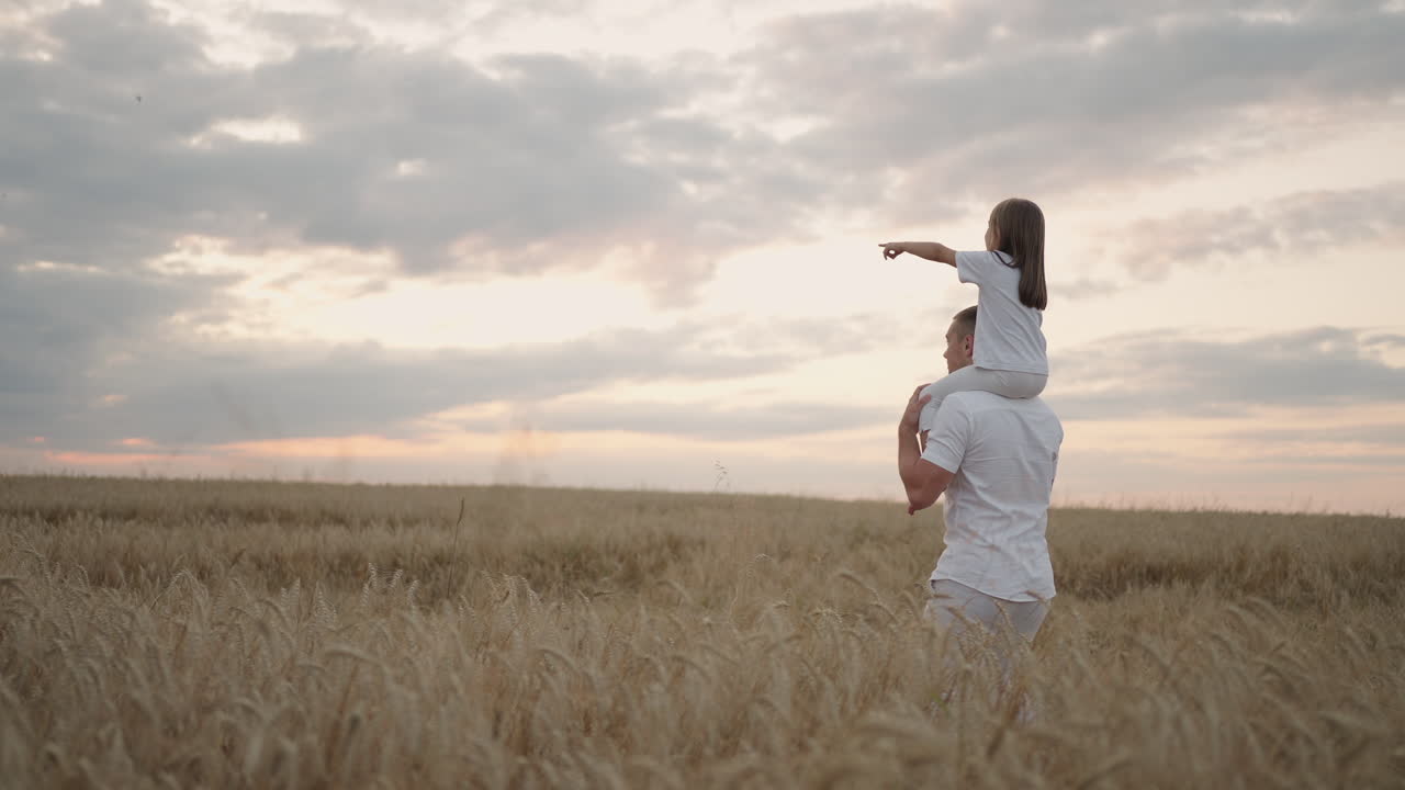 아빠는 어깨에 사랑하는 작은 건강한 딸을  ⁇ 에  ⁇ 고 있습니다. 슬로우 모션으로 딸은 아버지와 함께 필드에서  ⁇ 고 자유롭고 행복하게 손을 들어 올립니다. 필드에서  ⁇ 고 있습니다.