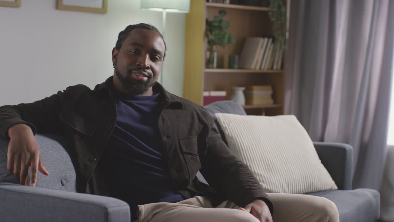 retrato de um jovem sorridente relaxando em casa sentado no sofá
