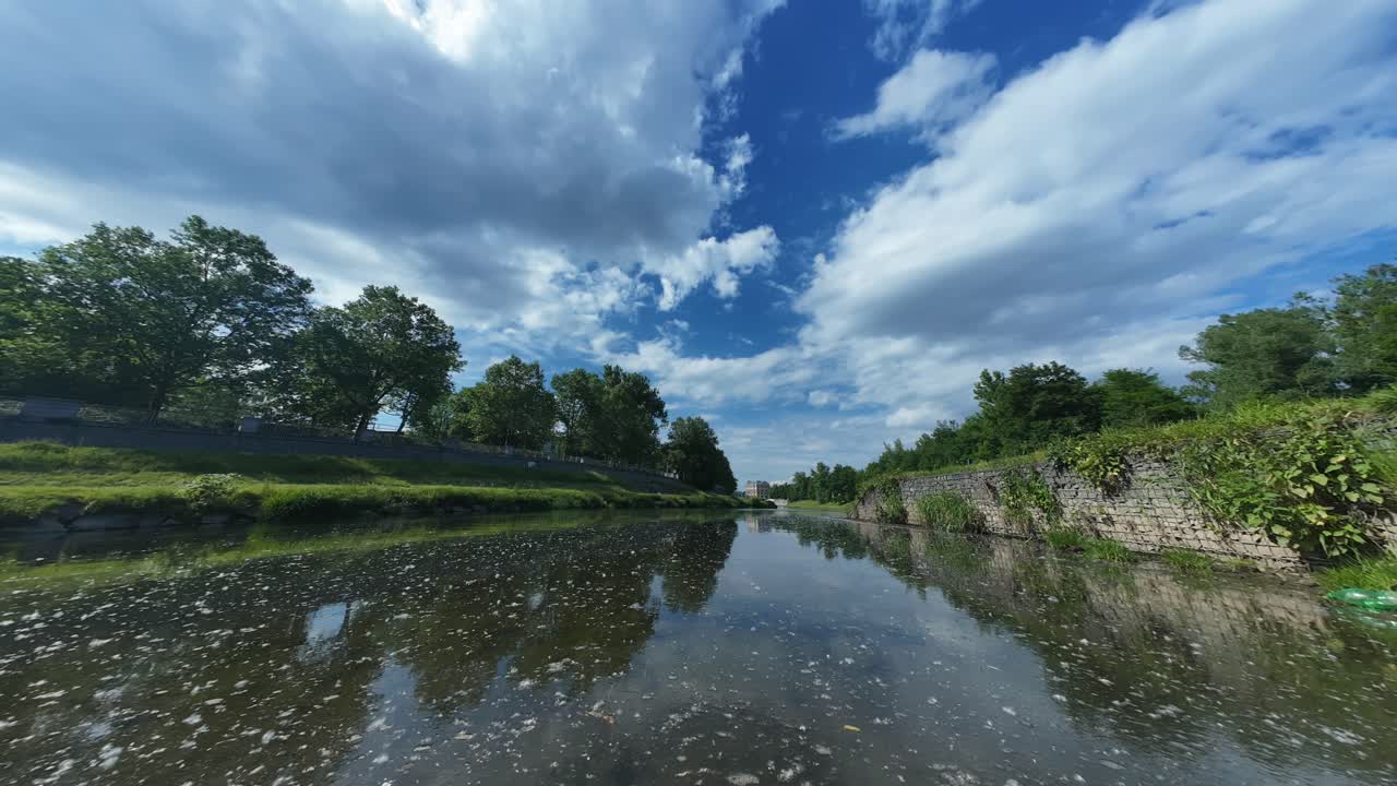 el lapso de tiempo de una vía fluvial serena con exuberante vegetación bajo un vasto cielo con nubes dispersas