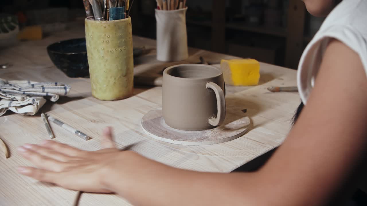 mujer joven alfarero rodando un pequeño pedazo de arcilla