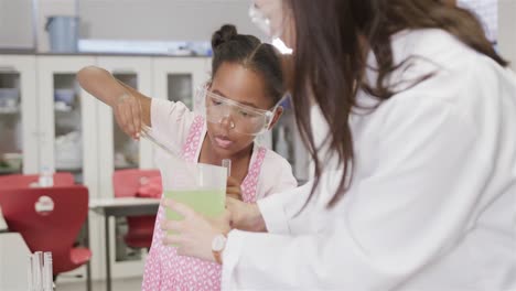 focused diverse female teacher and elementary school schoolgirl in lab in slow motion