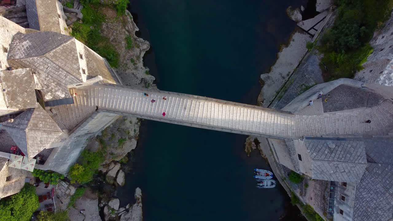 Aerial view looking down on famous Mostar Bridge with Neretva river on a quiet summer's morning