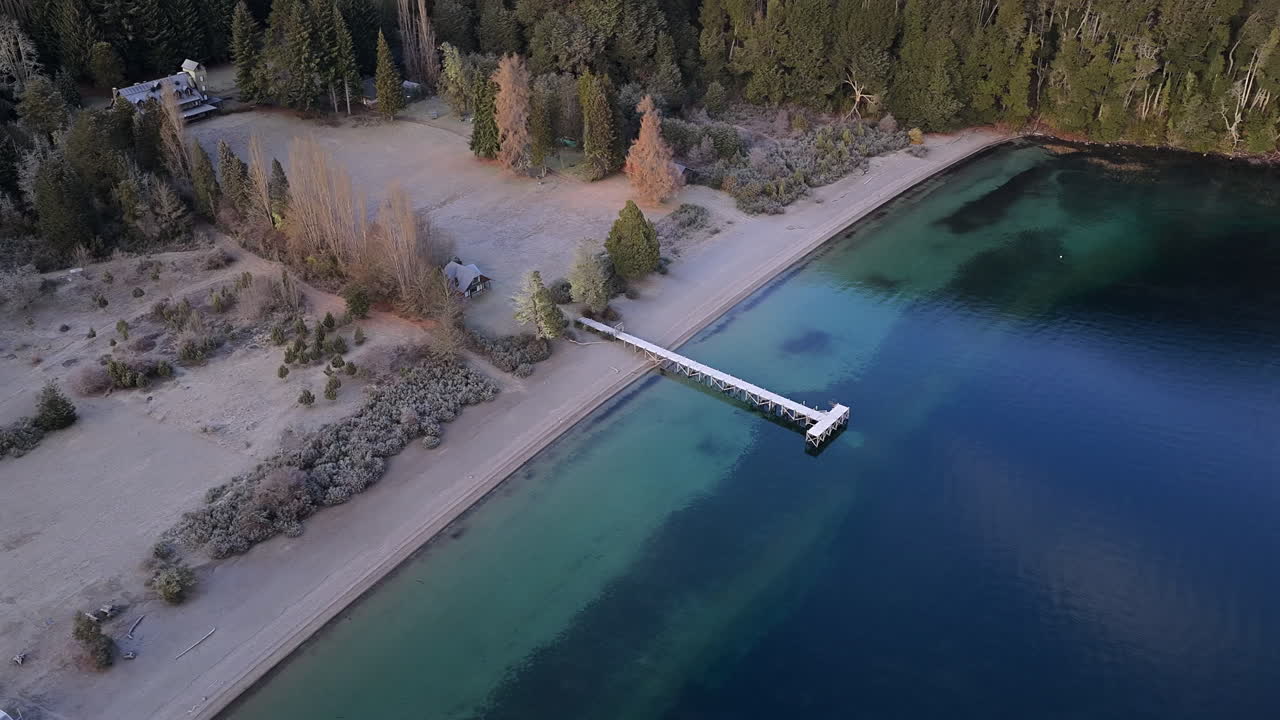Villa La Angostura, Neuquen, Patagonya, Arjantin yakınlarındaki Nahuel Huapi Milli Parkı'nda Lago Espejo'nun kumlu kıyı şeridi ve ahşap iskelesi, buzul unu ve volkanik tortudan kaynaklanan turkuaz göl rengi, yörüngede.