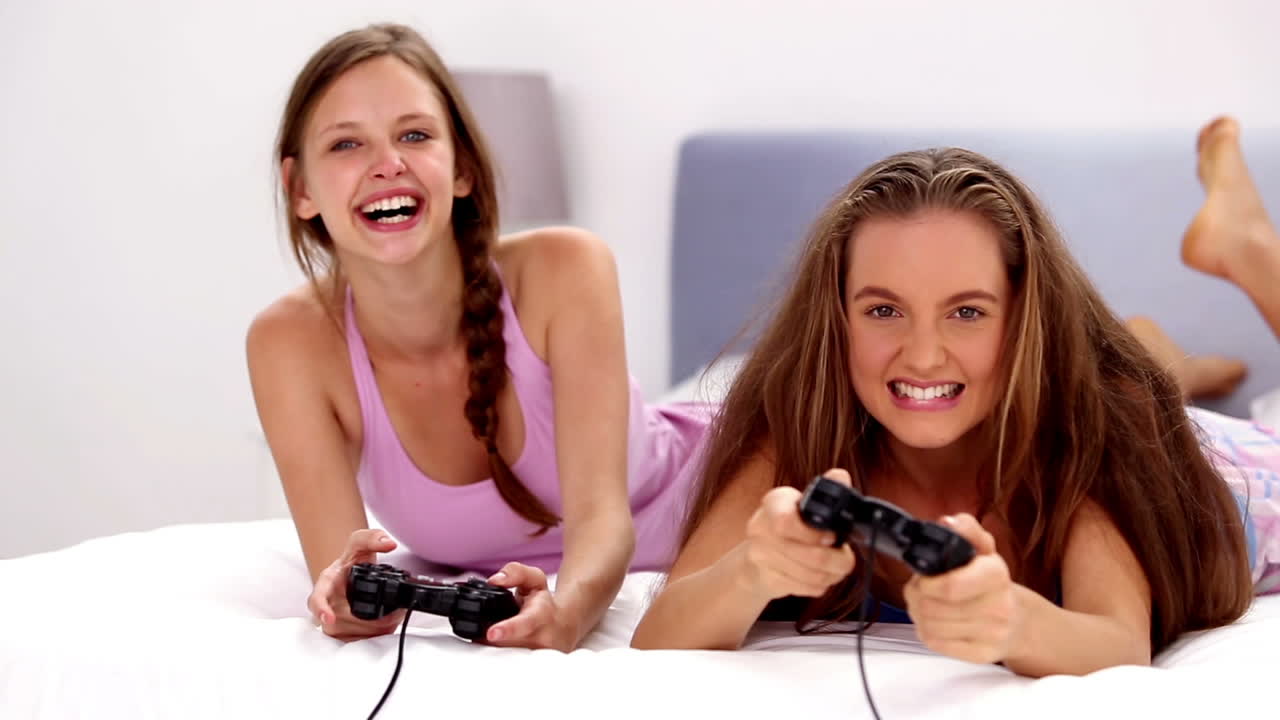 chicas emocionadas jugando videojuegos en la cama