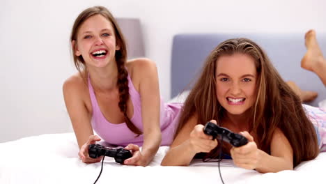 excited girls playing video games on bed