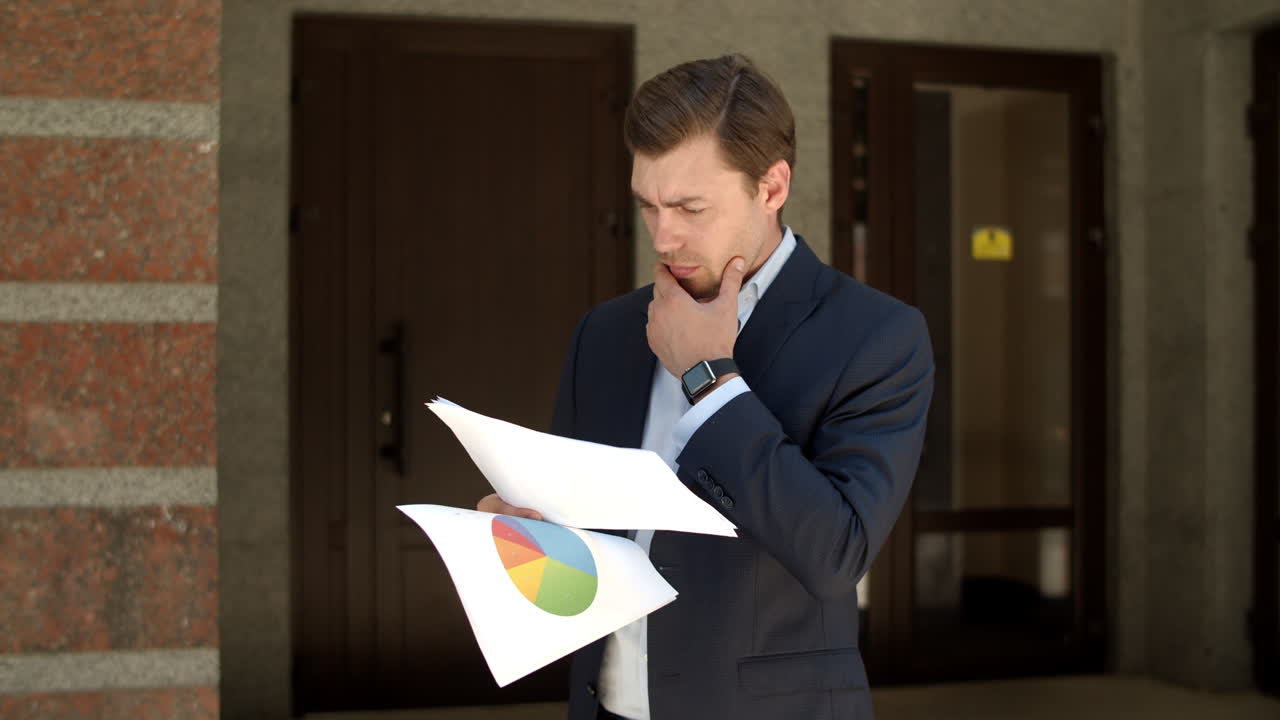 Closeup businessman standing near building. Man standing in suit with documents