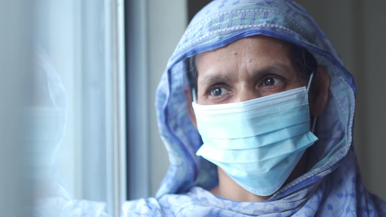 mujer mayor con una máscara mirando por una ventana